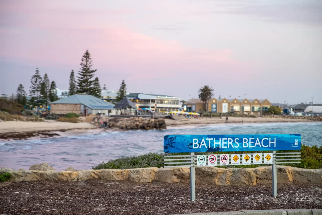 Bathers Beach, Fremantle. ALT: Bathers Beach in Fremantle, Western Australia, featuring the beachfront foreshore, calm coastal waters and waterfront dining at sunset.