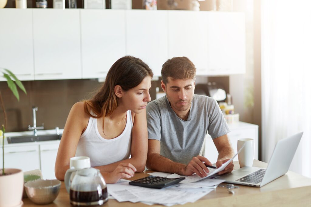 Couple reviewing finances and paperwork at home to calculate how much they can afford when buying a property together