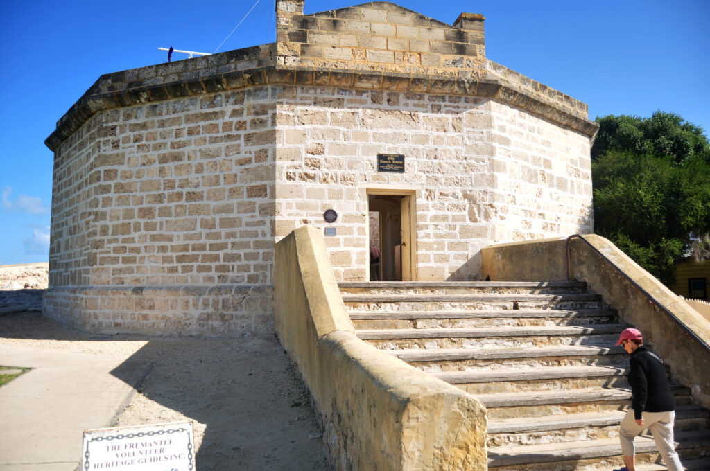 Historic Round House building in Fremantle, Western Australia, with limestone walls, stone steps and a visitor approaching the entrance on a sunny day.