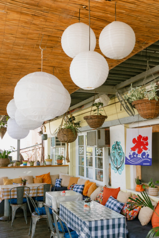 Outdoor seating at Hinata Café in Fremantle with hanging plants, paper lanterns, and colourful cushions.