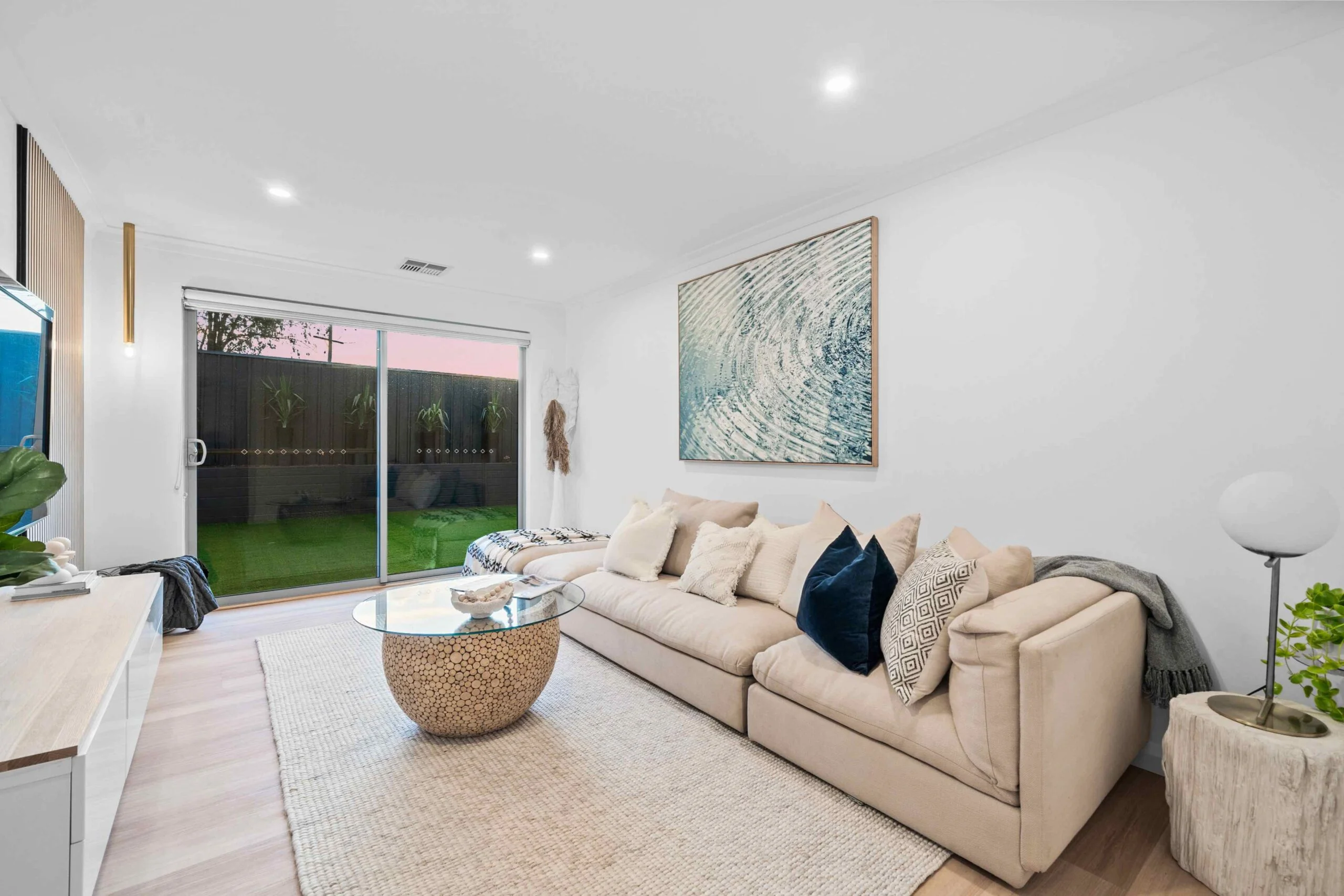 Bright living room in a Willetton rental property with beige sofa, glass coffee table, and sliding doors to the backyard manged by semple property group property management Perth.